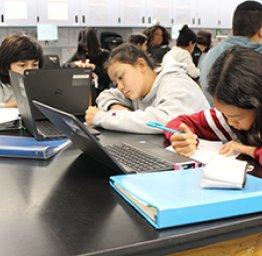 students working on laptops in classroom