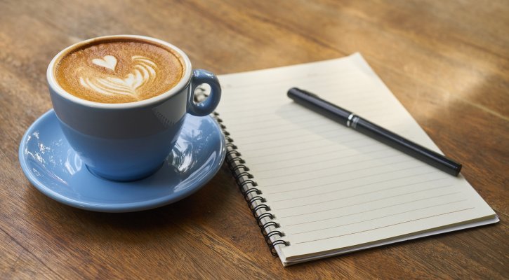 coffee, notebook, and pen on table