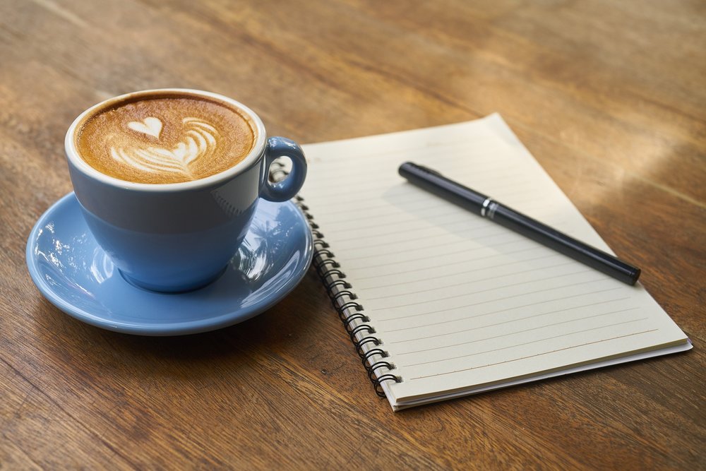 coffee, notebook, and pen on table